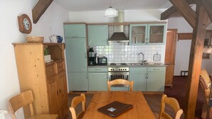 Una cocina con gabinetes color turquesa, una mesa de comedor de madera y sillas.