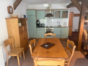 Une cuisine avec des armoires de couleur turquoise, une table à manger en bois et des chaises.