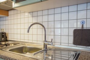 A kitchen with a stainless steel sink, a built-in oven, and a microwave. - Lovely Apartment with Balcony in Solzow Farmhouse (Südmüritz)