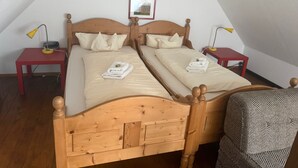 Un dormitorio con dos camas individuales, cabeceros de madera, mesitas de noche con lámparas y un cuadro enmarcado en la pared.