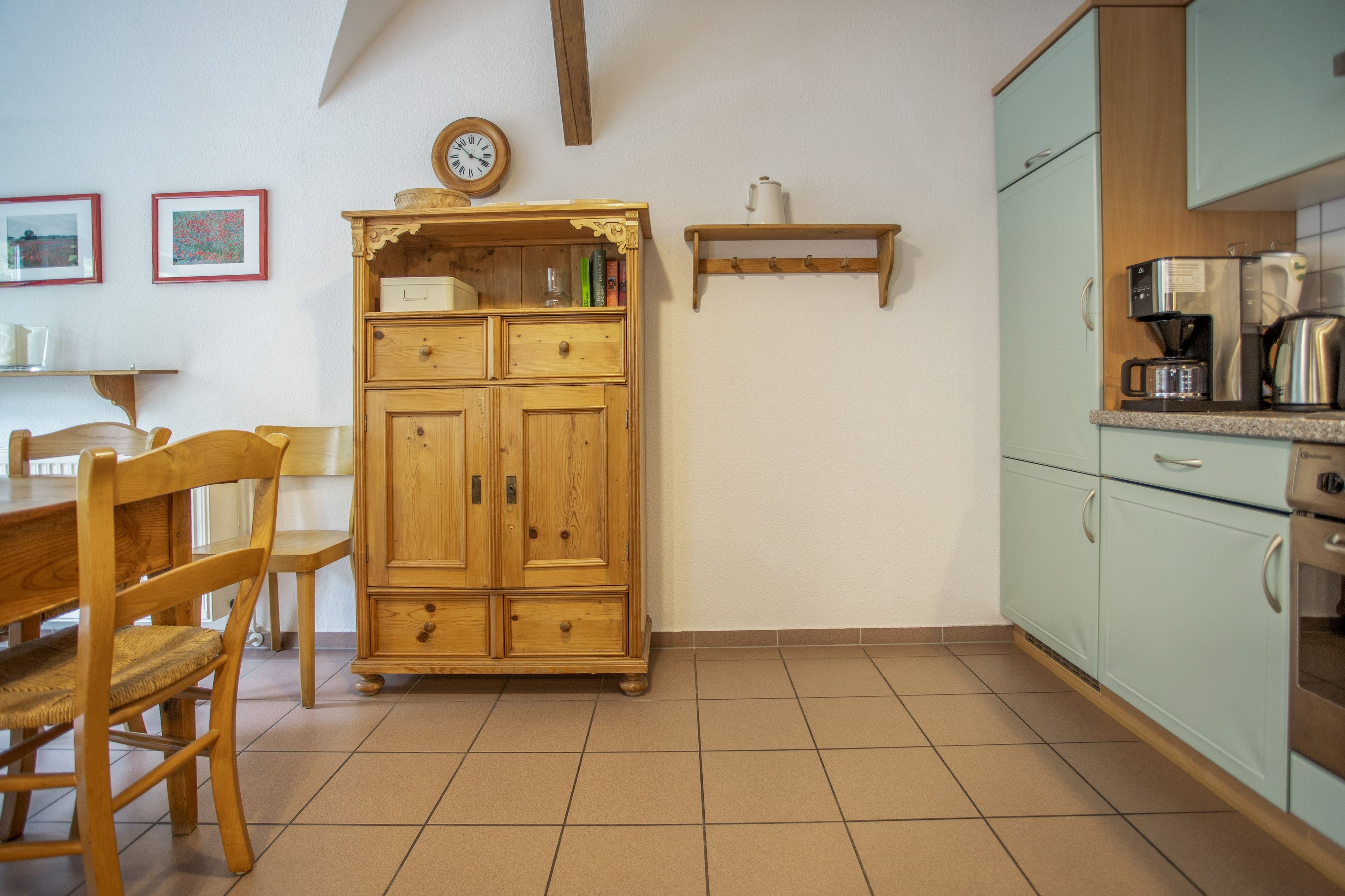 Eine Küche mit einem Holzkorpus, einer Kaffeemaschine und einer Uhr an der Wand.