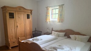 A bedroom with a wooden bed, a wardrobe, a window with curtains, and a nightstand. - Apartment '4' with Shared Garden and Wi-Fi (Südmüritz)