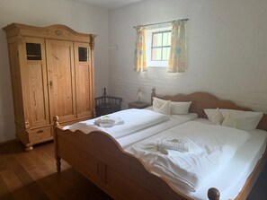 Une chambre à coucher avec un lit en bois, une armoire, une fenêtre avec des rideaux et une table de chevet.