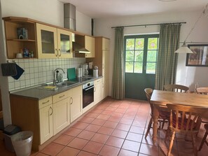 Cuina amb zona de dinar, incloent armaris, un rentapeus i una finestra amb cortines.