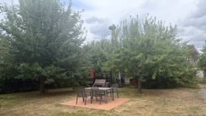 An outdoor patio area with a table and chairs, surrounded by trees and a grill. - Apartment '4' with Shared Garden and Wi-Fi (Südmüritz)