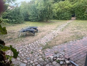 Un sendero pavimentado que conduce a un espacio con asientos y una estructura de metal.
