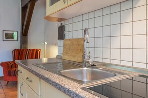 Cuina amb taulell de granit, rentamicroones d'acer inoxidable i taula de tall de fusta.