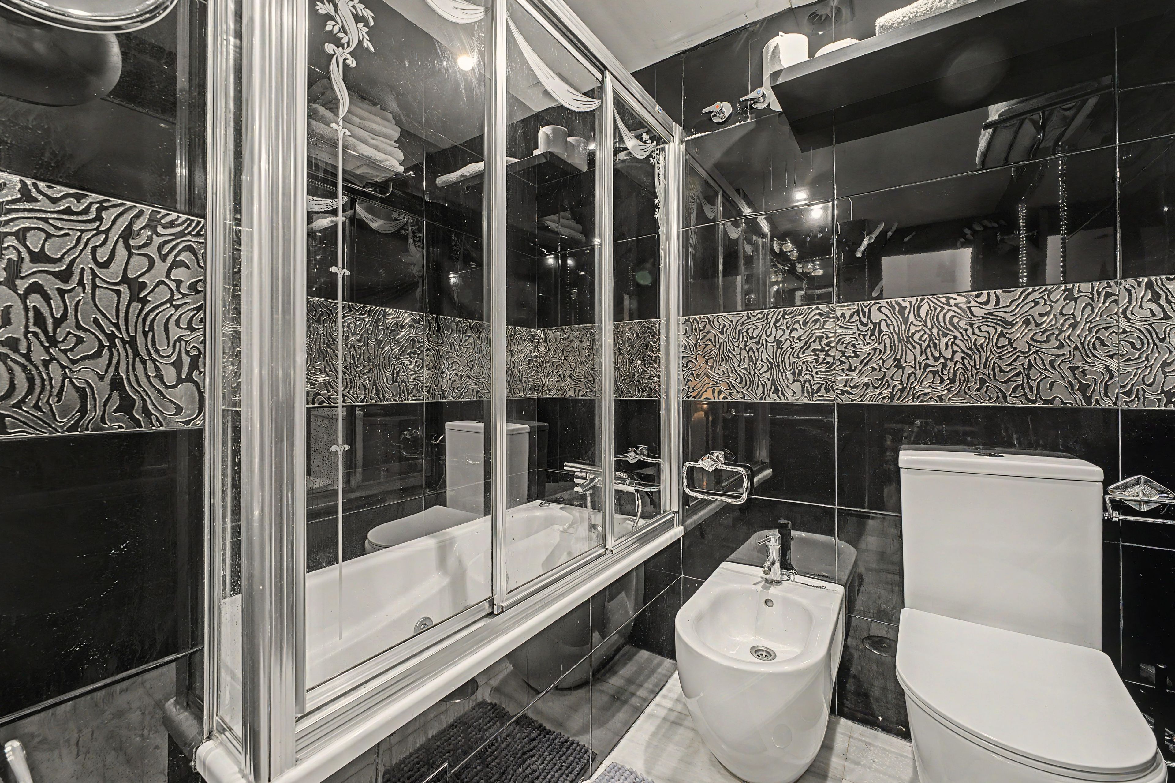 A modern bathroom with a glass-enclosed shower, a bidet, and a toilet.