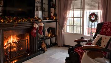 Una sala de estar acogedora con chimenea, un árbol de Navidad y decoración festiva.