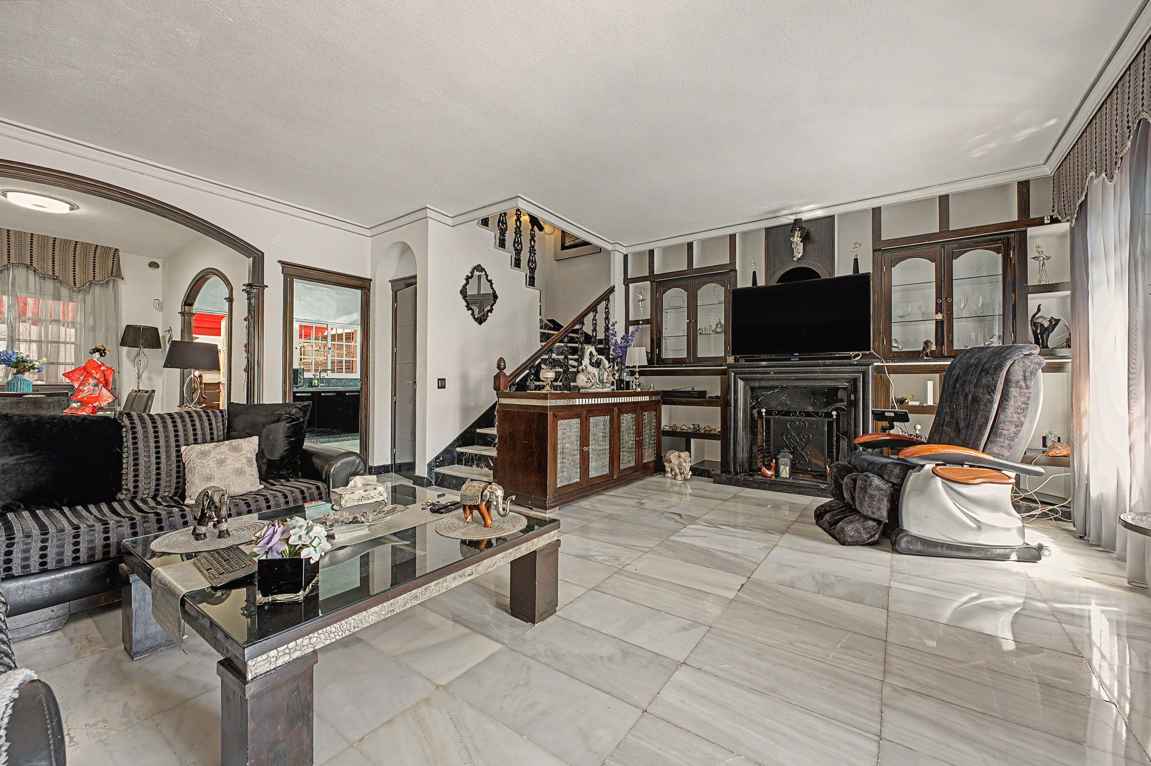 A spacious living room with a fireplace, a sofa, a coffee table, and a television.