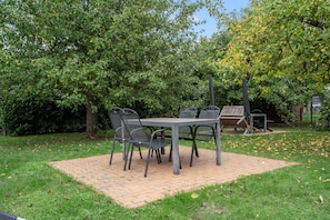 An outdoor patio with a table and chairs, surrounded by trees and a grassy area. - Apartment '6 Ground Floor' with Shared Garden (Südmüritz)