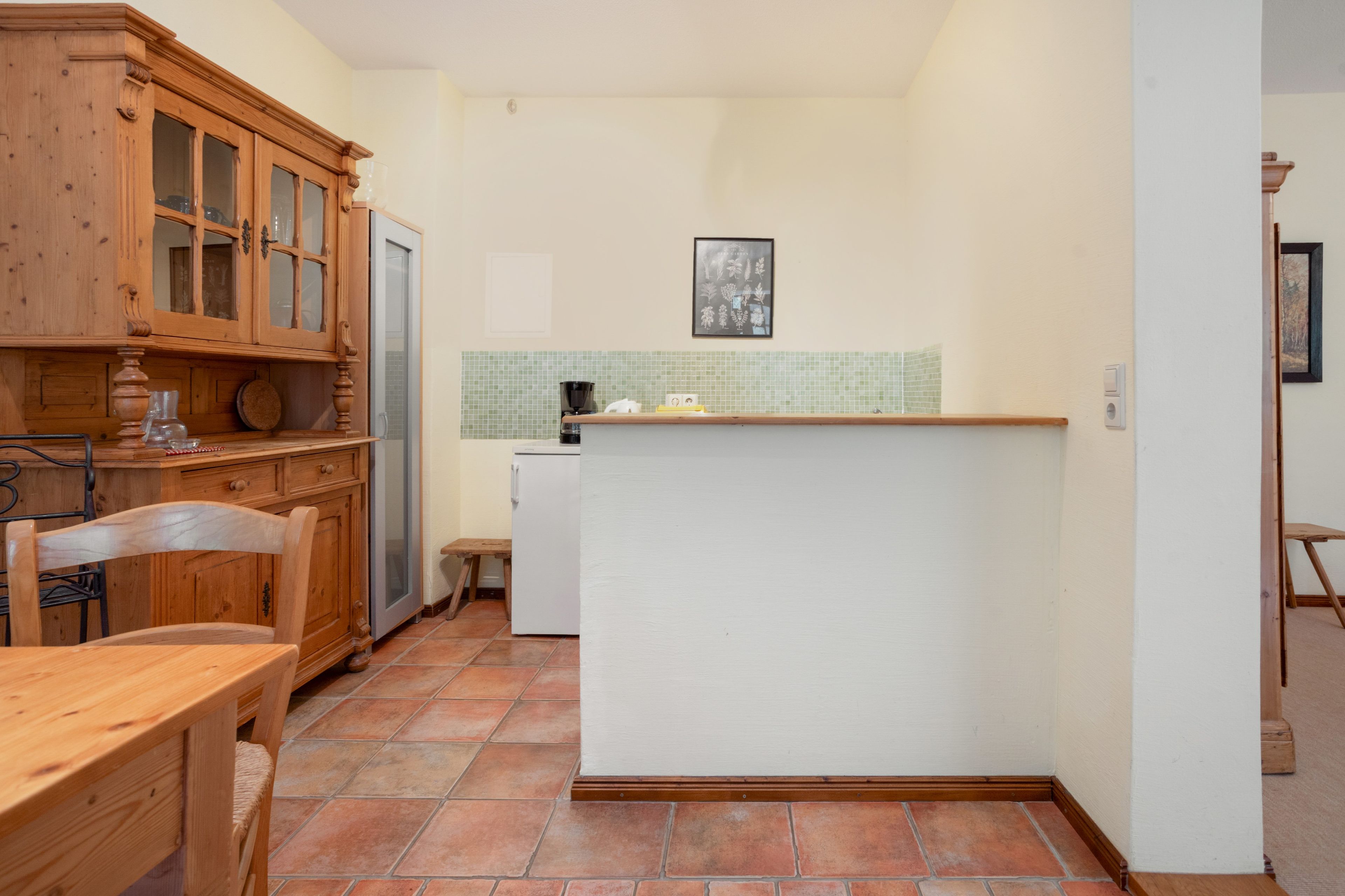 Eine kleine Küche mit Holzausstattung, einem weißen Kühlschrank und einer gefliesten Spritzschutzwand.