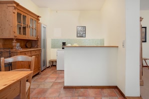 A compact kitchen with wooden cabinetry, a white refrigerator, and a tiled backsplash. - Apartment '6 Ground Floor' with Shared Garden (Südmüritz)