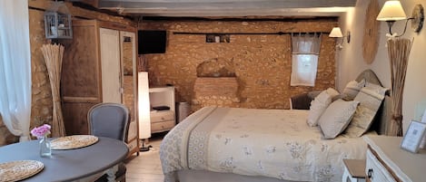 Un dormitorio acogedor con cama, mesita de noche, lámpara y una pequeña mesa con una silla.