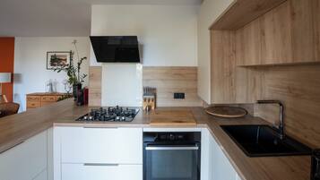 Een moderne keuken met een inbouwgasfornuis, oven en vaatwasser.