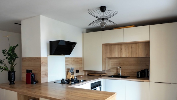A modern kitchen with a central island, wooden cabinets, and a built-in TV.