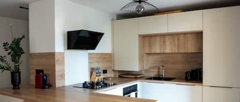 A modern kitchen with a central island, wooden cabinets, and a built-in TV.