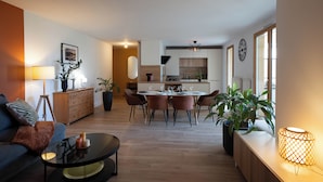 A modern living room with a sofa, coffee table, and a dining area with chairs and a table.