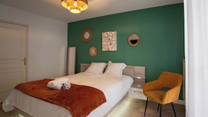 A bedroom with a bed, a chair, a nightstand, and wall decorations.