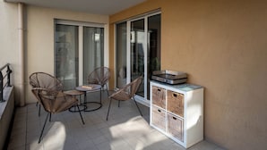 A balcony with wicker chairs, a small table, and a pizza oven.