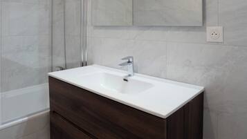 Une salle de bain moderne avec un meuble-lavabo blanc, une cabine de douche en verre et un grand miroir.
