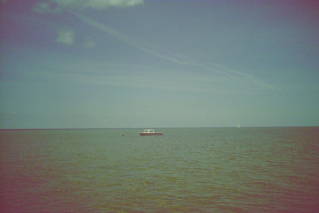 Une mer calme avec un petit bateau à l’horizon.