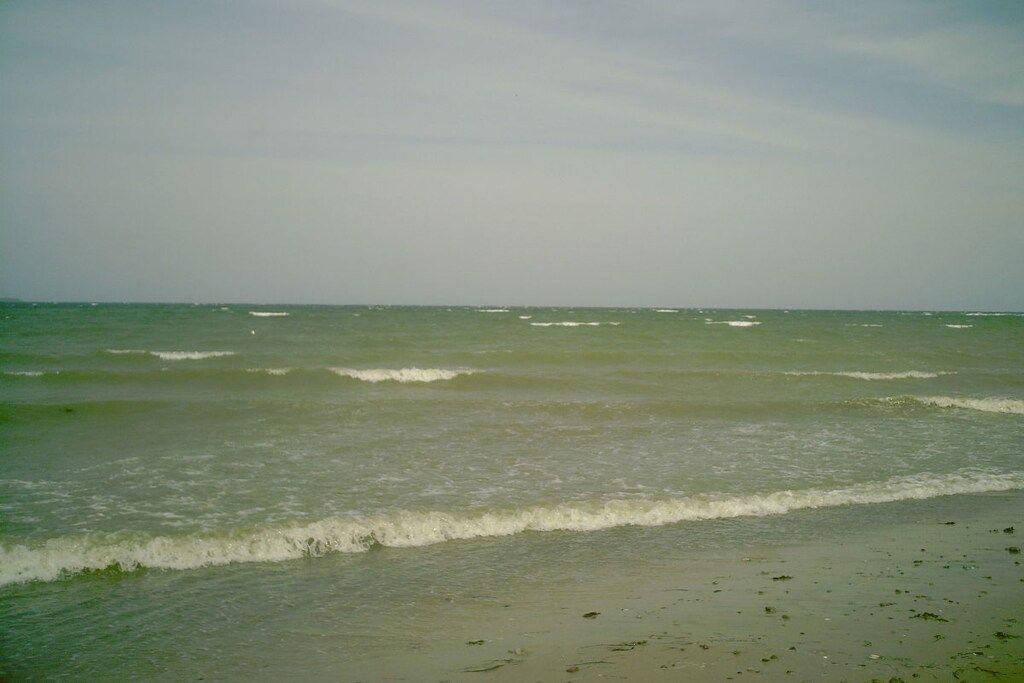 A beach with waves and a clear sky.
