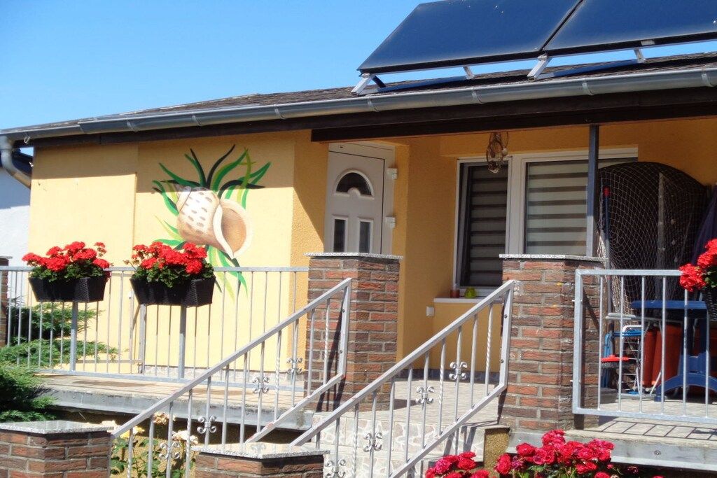 A building with a yellow facade, a pineapple mural, and a solar panel on the roof.