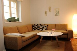 Ein Wohnzimmer mit einer Couch, einem runden Tisch und einem Fenster mit einer Fischdekoration.