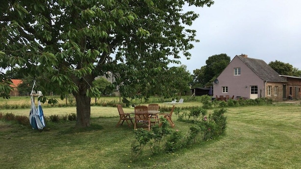 A grassy outdoor area with a picnic table and chairs, a large tree, and a house in the background. - on the hereditary village headman's farm (Buchholz)