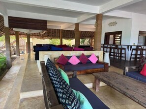 An outdoor seating area with multiple sofas and benches, some with cushions. - Palafitta Zanzibar (Pingwe)