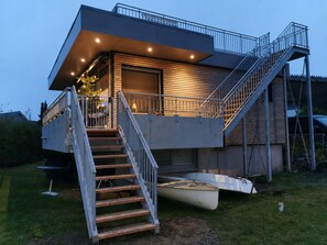 Ein modernes Haus mit einer Treppe, die zu einer Terrasse, einem Boot und einer Garage führt.