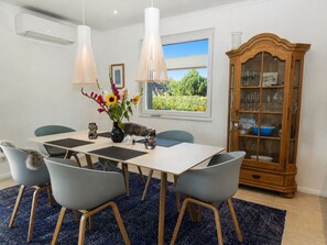 A dining area with a table, chairs, a vase with flowers, and a cabinet with glassware. - fewo1846 - Berglyk 1 - Beach house with a rooftop terrace, garden, and 2 bedrooms (Glücksburg)