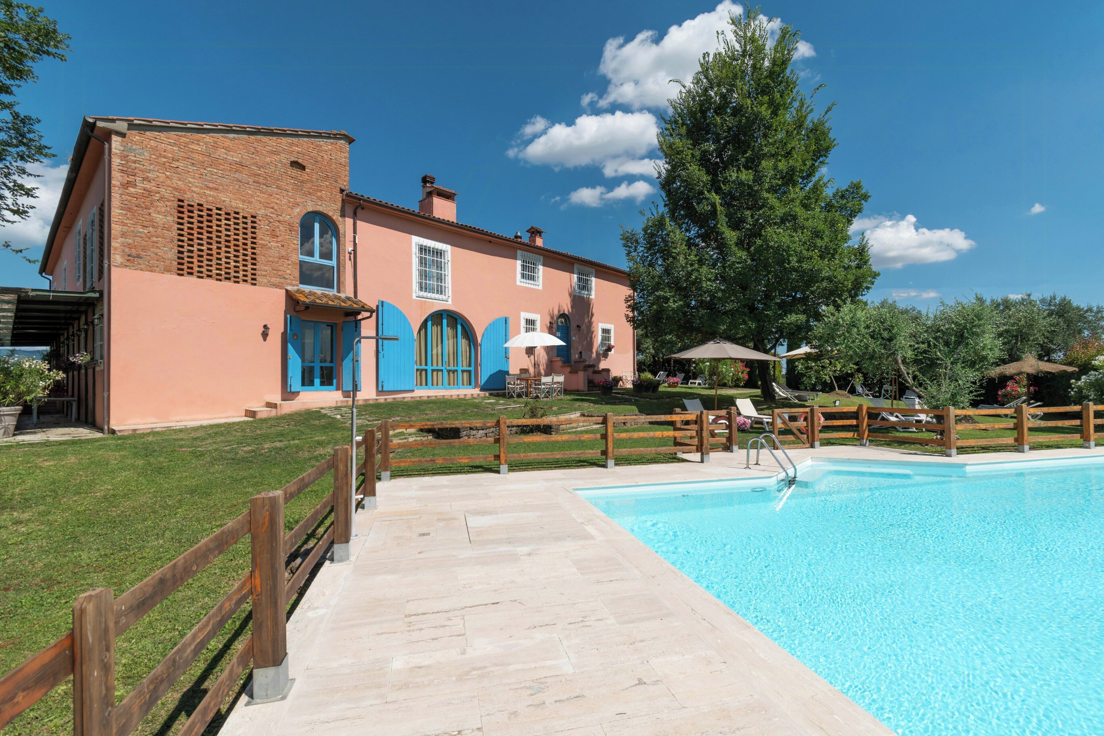 Un bâtiment à deux étages doté d’une piscine, d’une clôture en bois et d’une pelouse verdoyante.