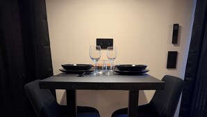 Ein Esstisch mit zwei Stühlen, zwei Weingläsern und zwei Schüsseln auf einer schwarzen Tischdecke.