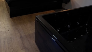 Ein modernes Schlafzimmer mit Bett, Nachttisch und einer schwarzen Badewanne.
