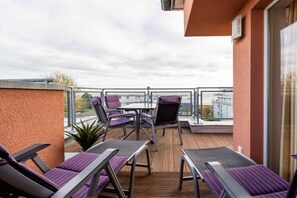 A balcony with lounge chairs and a table, overlooking a cityscape. - Holiday apartment with 3 bedrooms (Großenbrode)