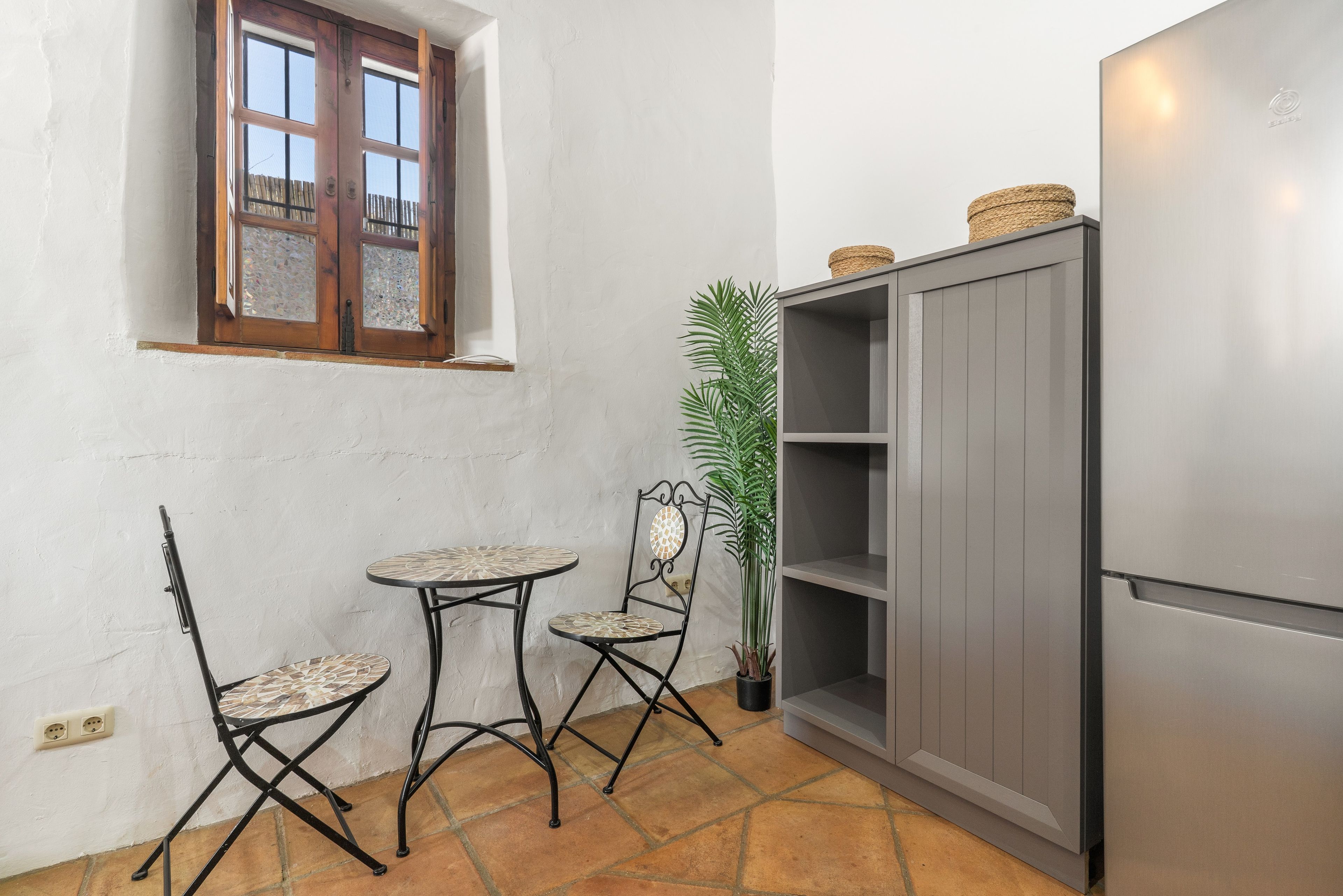 Una cocina compacta con un pequeño comedor, que incluye una mesa, sillas, un refrigerador y una ventana con vistas.