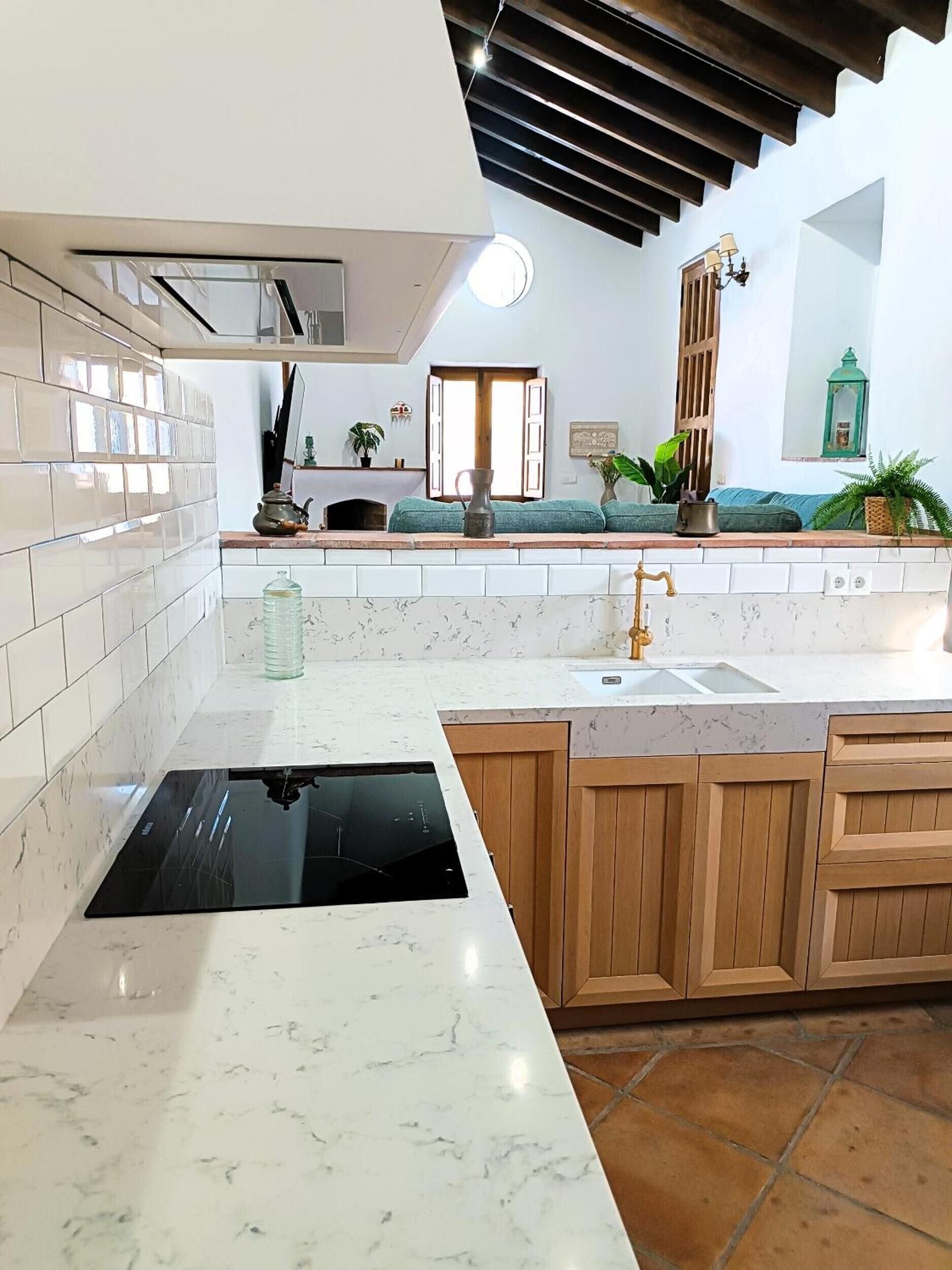 Una cocina moderna con estufa integrada, un lavaplatos, armarios de madera y salpicadero de azulejos.