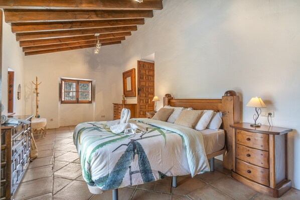 Une chambre à coucher avec un lit en bois, des tables de chevet, une commode, une fenêtre et un plafond en bois.