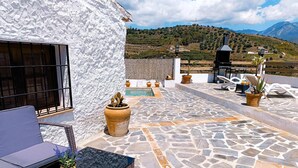 Une terrasse sur le toit, dotée d’un sol en pierre, de mobilier d’extérieur, de plantes en pot et offrant une vue sur un paysage montagneux.
