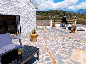 Une terrasse sur le toit, dotée d’un sol en pierre, de mobilier d’extérieur, de plantes en pot et offrant une vue sur un paysage montagneux.