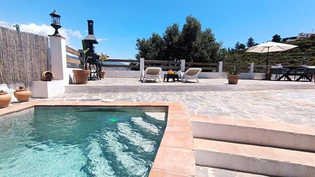 Un espace piscine offrant une vue dégagée sur la mer, avec des chaises longues et un coin barbecue.