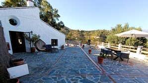 Un espace patio avec un sol en pierre, des sièges d’extérieur et des plantes en pot.