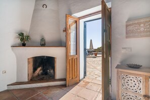 A room with a fireplace, a door leading outside, and a small table with a decorative bowl.