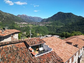 A mountainous landscape with terracotta-roofed buildings and a village in the valley. - Sompriezzo: Lake View (Tremosine)