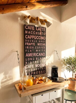 A kitchen counter with a coffee machine, a tray with croissants, and a sign listing coffee types. - Sompriezzo: Lake View (Tremosine)