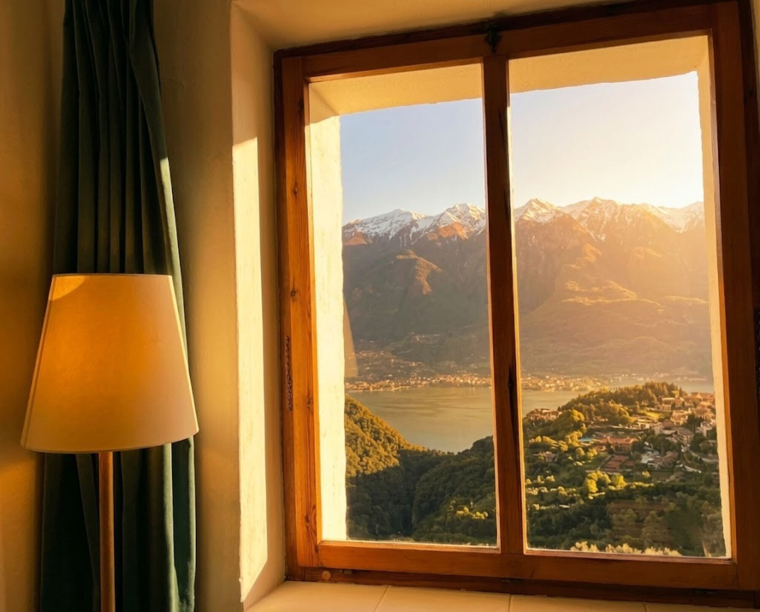 Una habitación con un amplio ventanal que ofrece vistas a montañas y un lago.