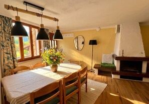 A dining area with a table, chairs, a vase of flowers, and a fireplace. - Sompriezzo: Lake View (Tremosine)