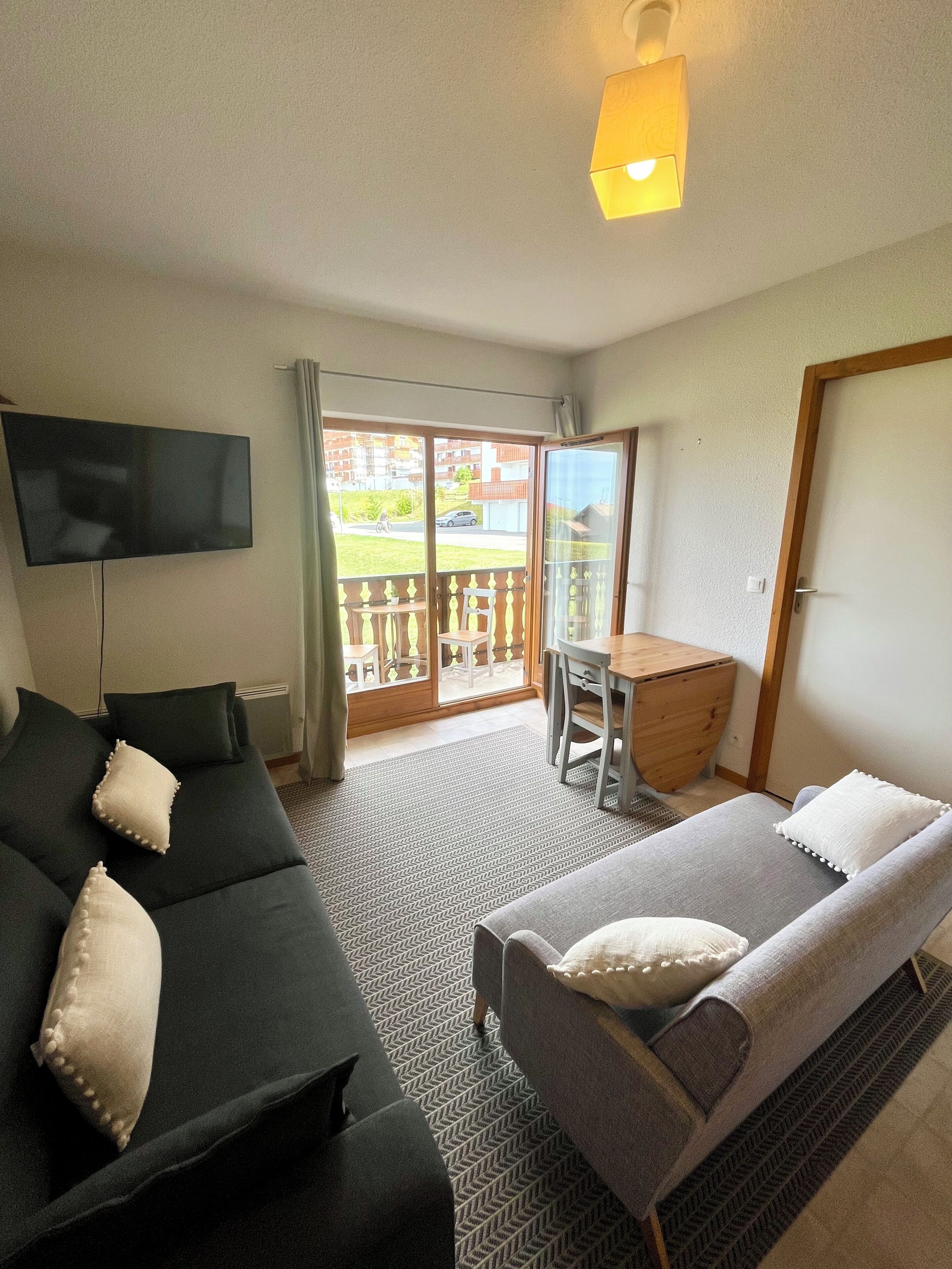 Ett hotellrum med en soffa, en säng, en TV, en balkong och en matplats.